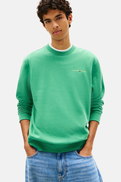 Tommy Jeans groene rondehals sweatshirt, gedragen met een wijde blauwe jeans en witte sneakers.