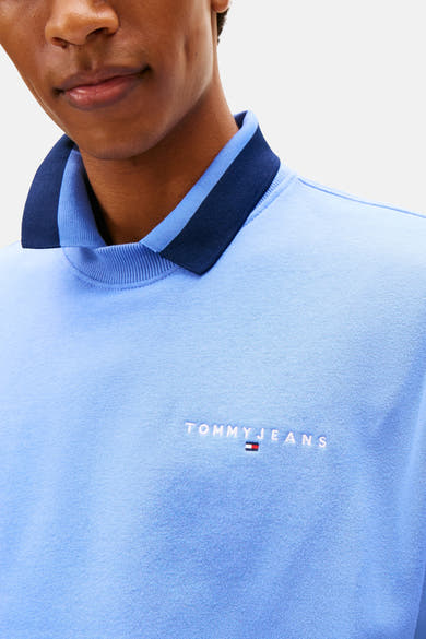 Blauwe sweater van TOMMY JEANS, met een marineblauwe kraag en het geborduurde logo op de voorkant.