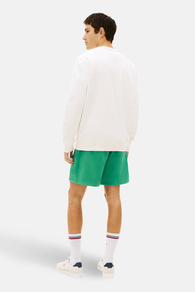Witte sweater van TOMMY JEANS, gedragen met een groene korte broek en gestreepte sokken, achterzicht.