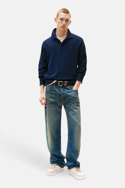 Pull bleu par Tommy Jeans, porté avec un jean ample et des baskets crème.
