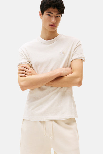 T-shirt beige à manches courtes de TOMMY JEANS, porté avec un short assorti en maille gaufrée.