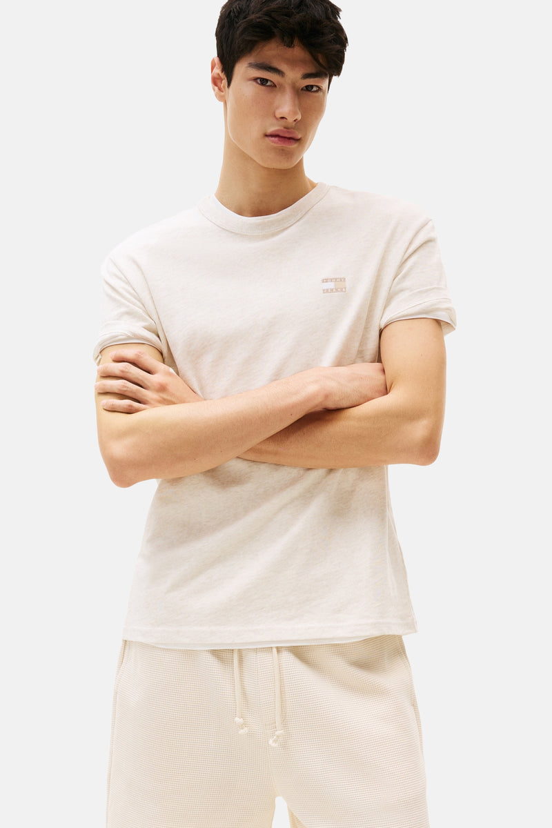T-shirt beige à manches courtes de TOMMY JEANS, porté avec un short assorti en maille gaufrée.