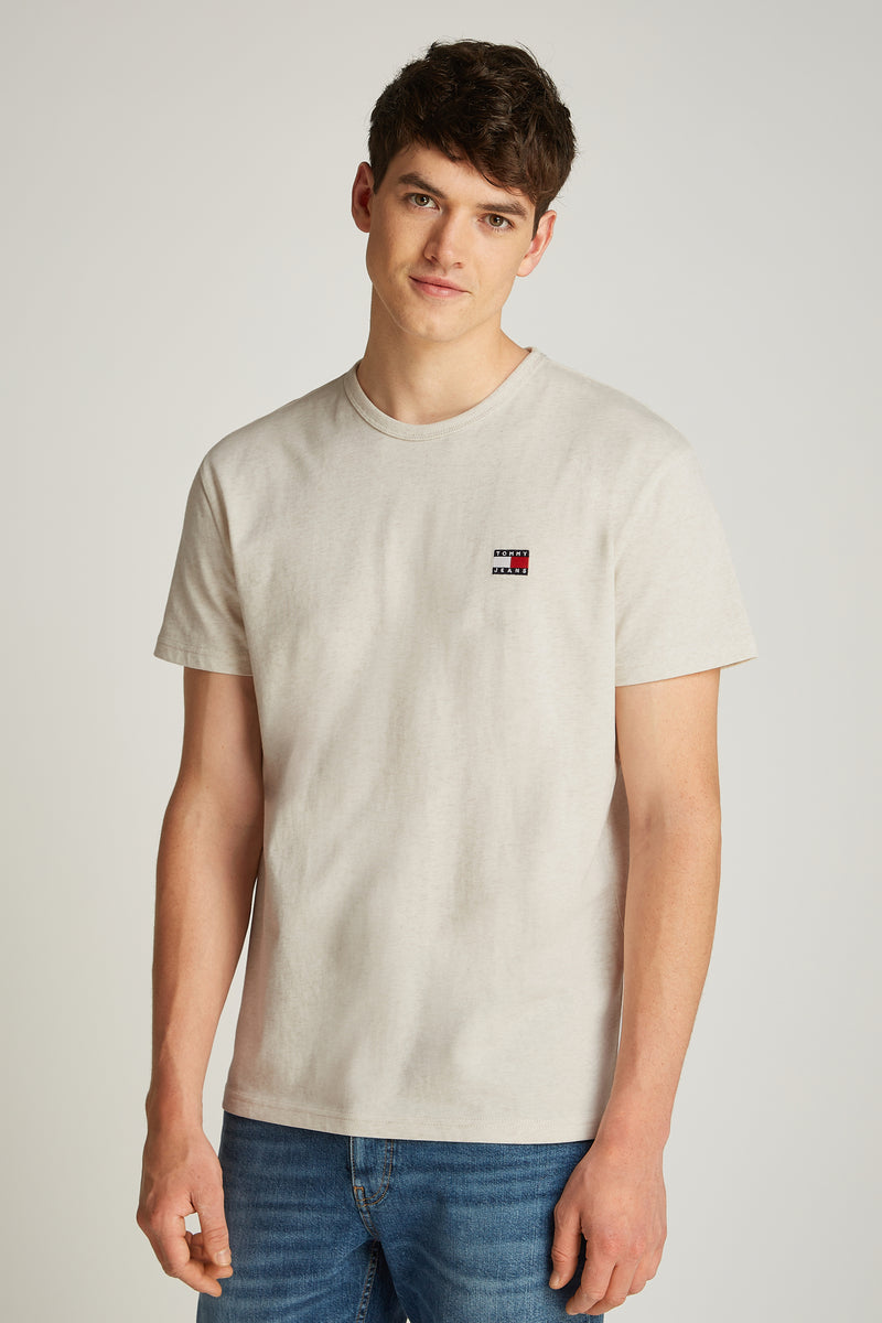 Ecru T-shirt met korte mouwen van TOMMY JEANS, met discreet logo, gedragen met een spijkerbroek.