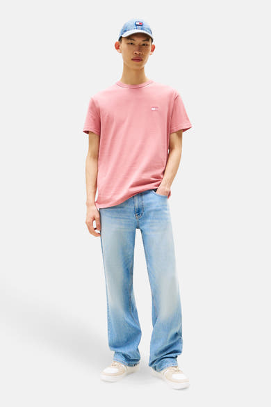 T-shirt rose à manches courtes de TOMMY JEANS, porté avec un jean bleu délavé et une casquette en jean.
