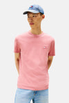 T-shirt rose à manches courtes de TOMMY JEANS, porté avec une casquette en denim et un jean.