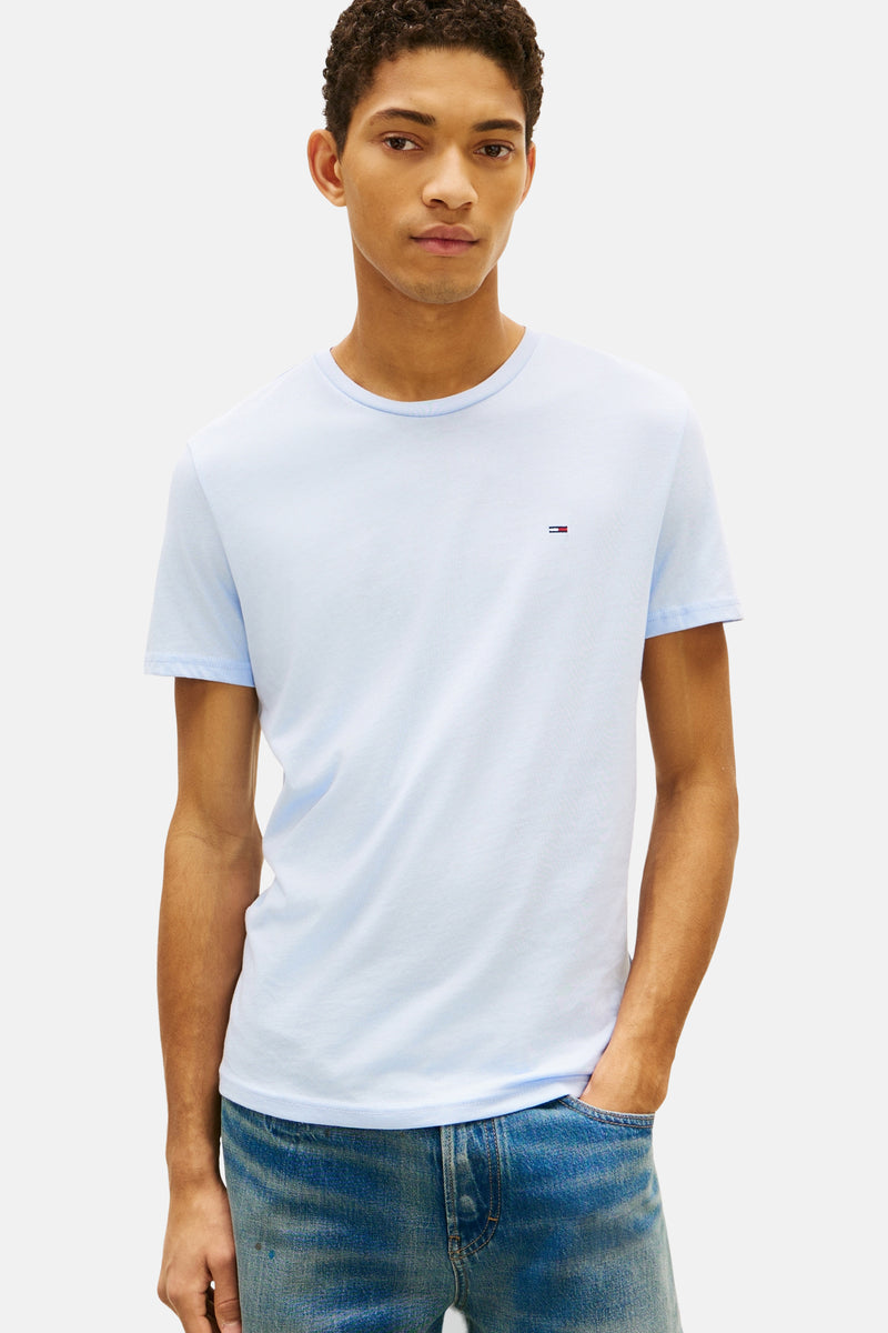 Blauw T-shirt met korte mouwen van TOMMY JEANS, gedragen met een verbleekte spijkerbroek en bruine schoenen.