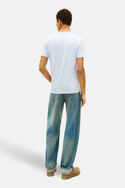 Blauw T-shirt met korte mouwen van TOMMY JEANS, gedragen met een wijde blauwe jeans en bruine schoenen.