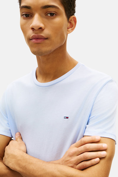 Blauw T-shirt met korte mouwen van TOMMY JEANS, met discreet logo op de voorkant, gedragen door een man met gekruiste armen.