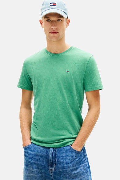 Groen T-shirt met korte mouwen van Tommy Jeans, gedragen met een crèmekleurige trui die is vastgebonden en een spijkerbroekshort.
