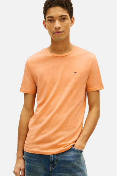 Oranje T-shirt met korte mouwen van TOMMY JEANS, gedragen met een wijde blauwe jeans en witte sneakers.