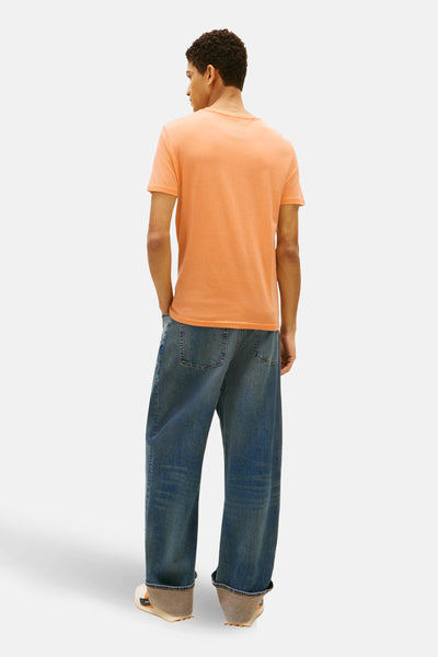 Oranje T-shirt met korte mouwen van TOMMY JEANS, gedragen met een wijde spijkerbroek, achtergezicht.