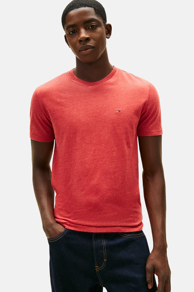 Rood T-shirt met korte mouwen van TOMMY JEANS, gedragen met een donkerblauwe wijde jeans en een zwarte sporttas.