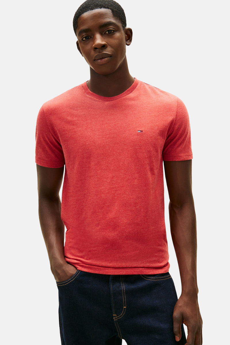 Rood T-shirt met korte mouwen van TOMMY JEANS, gedragen met een donkerblauwe wijde jeans en een zwarte sporttas.