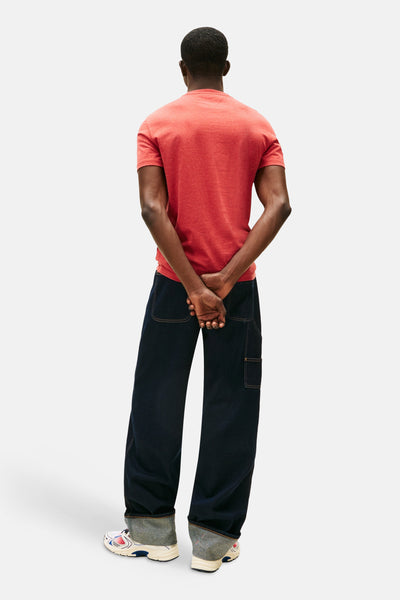 Rood T-shirt met korte mouwen van TOMMY JEANS, gedragen met een donkerblauwe broek en sportschoenen.