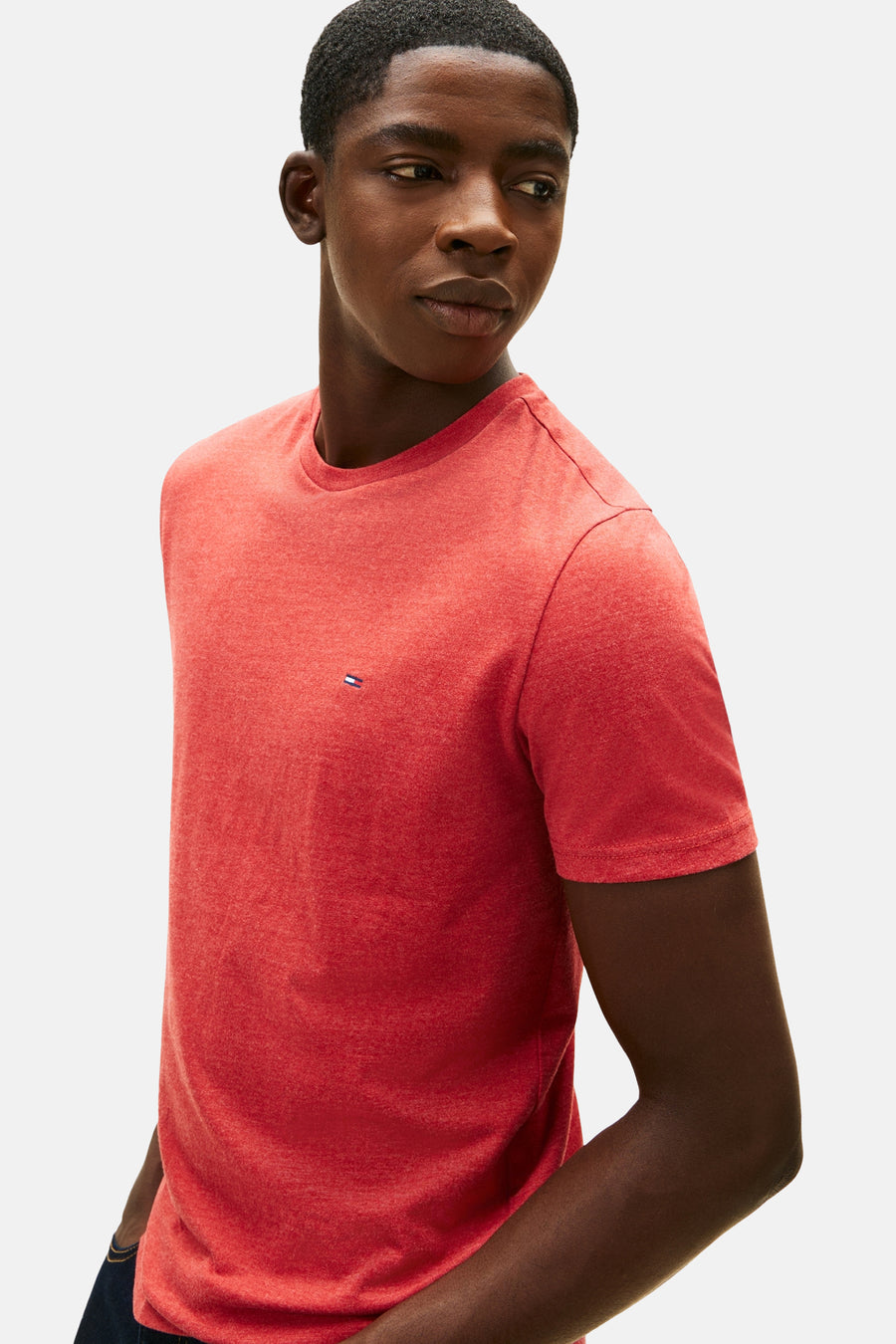 Rood T-shirt met korte mouwen van TOMMY JEANS, van gemêleerd tricot, gedragen door een man die opzij kijkt.