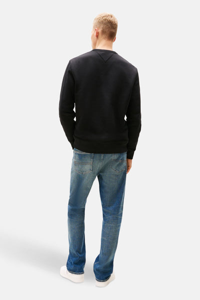 Zwarte rondehals sweatshirt van TOMMY JEANS, gedragen met een casual spijkerbroek en witte schoenen.