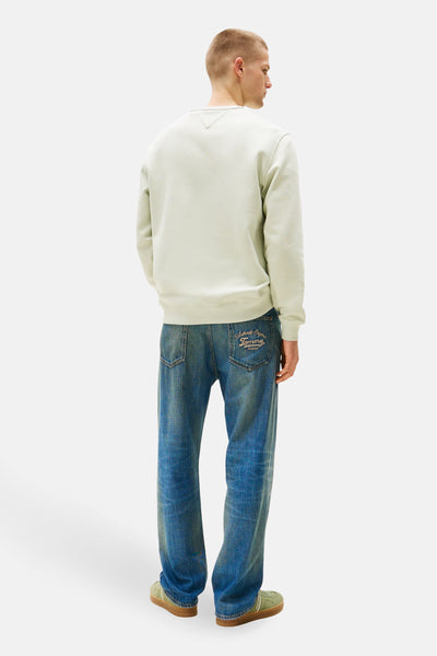 Sweat-shirt vert de TOMMY JEANS, avec un col rond et une coupe décontractée, porté avec un jean bleu.