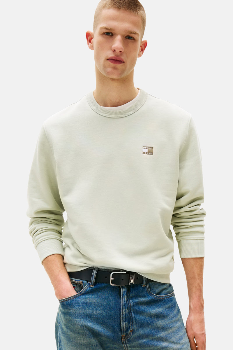Sweat vert de Tommy Jeans, porté avec un jean et une ceinture noire.
