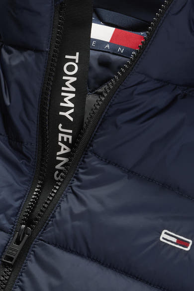 Blauwe mouwloze jas van TOMMY JEANS, ritssluiting met logo langs de sluiting, opgestikt logo onderaan.