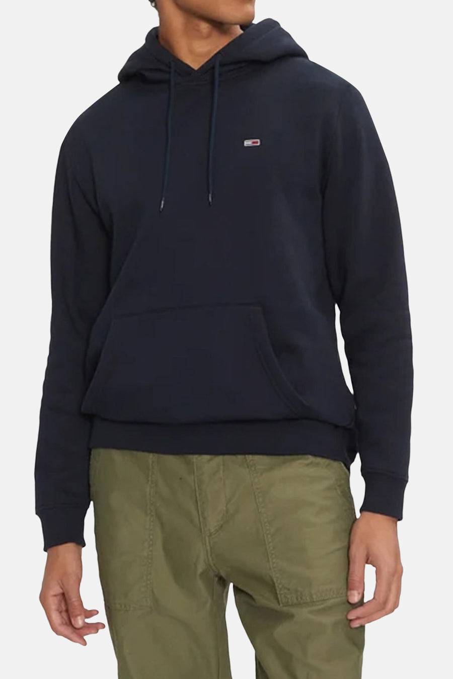 Sweat à capuche bleu de Tommy Jeans, avec cordon de serrage et poche kangourou sur le devant, porté avec un pantalon kaki.