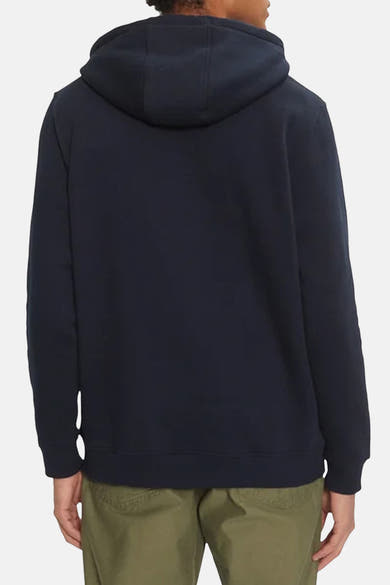 Sweat à capuche bleu par Tommy Jeans, avec capuche et coupe décontractée, porté avec un pantalon kaki.