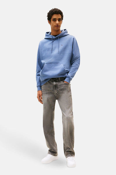 Sweat à capuche bleu de TOMMY JEANS, porté avec un jean gris et des baskets blanches.