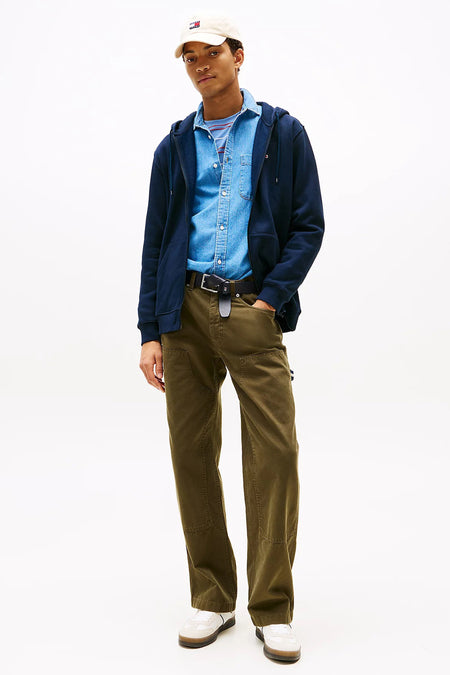 Gilet bleu de Tommy Jeans, porté sur une chemise en jean boutonnée et un pantalon cargo vert olive.