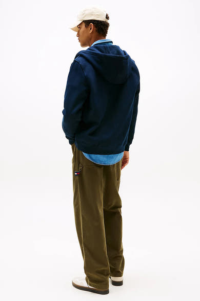 Sweat à capuche bleu marine de Tommy Jeans, porté avec une chemise en denim et un pantalon kaki.