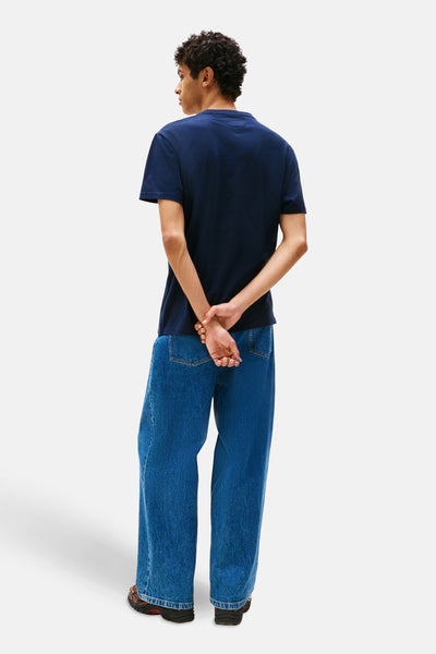 Blauw T-shirt met korte mouwen van TOMMY JEANS, gedragen met een wijde jeans en sportschoenen, achtergezicht.