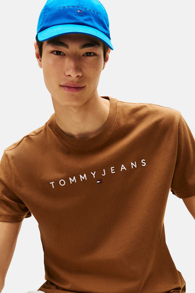Bruin T-shirt met korte mouwen van TOMMY JEANS met logo op de voorkant, gedragen met een blauwe pet.