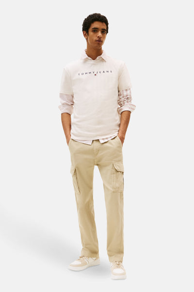 Beige T-shirt met korte mouwen van TOMMY JEANS, gedragen over een roze gestreept overhemd en met een beige cargobroek.
