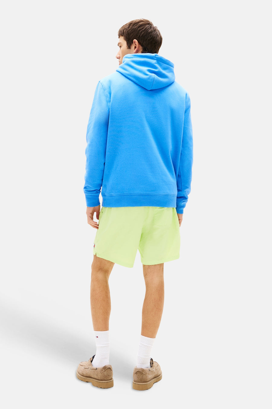 Blauwe hoodie van TOMMY JEANS, met capuchon, gedragen met een groene korte broek en bruine schoenen.