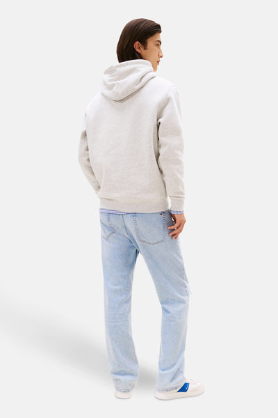 Grijze Tommy Jeans hoodie, gedragen met een geruit overhemd en een verbleekte spijkerbroek.