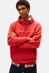 Rode hoodie van TOMMY JEANS gedragen met een geruit overhemd en een wijde jeans.