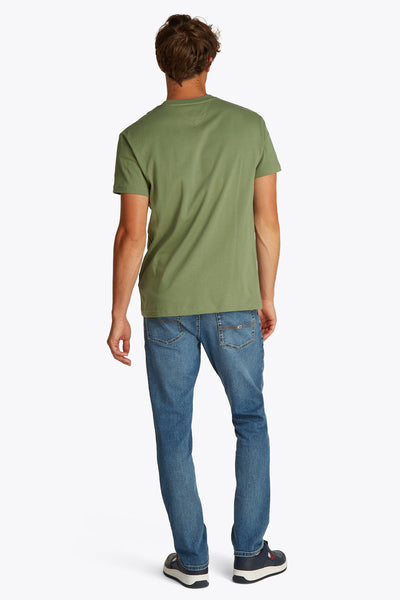Groen T-shirt met korte mouwen van TOMMY JEANS, gedragen met een blauwe spijkerbroek en blauwe sportschoenen, achtergezicht.