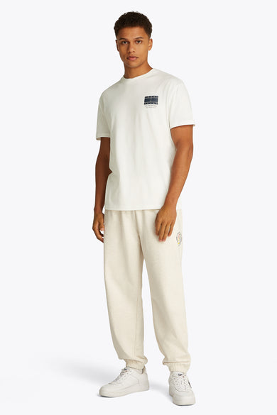 Wit T-shirt met korte mouwen van TOMMY JEANS, met een logo op de borst, gedragen met een joggingbroek.