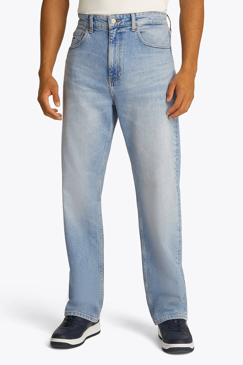 Rechte lichtblauwe spijkerbroek van Tommy Jeans, gedragen met marineblauwe en witte sneakers.