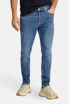 Tommy Jeans lichtblauwe tapered jeans, gedragen met beige sneakers.