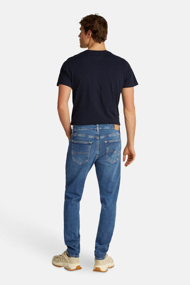 Lichtblauwe skinny jeans van TOMMY JEANS, met achterzakken en beige schoenen.