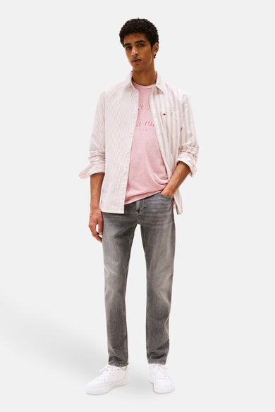 Jean fuselé gris moyen en denim de TOMMY JEANS, porté avec une chemise rayée et des baskets blanches.