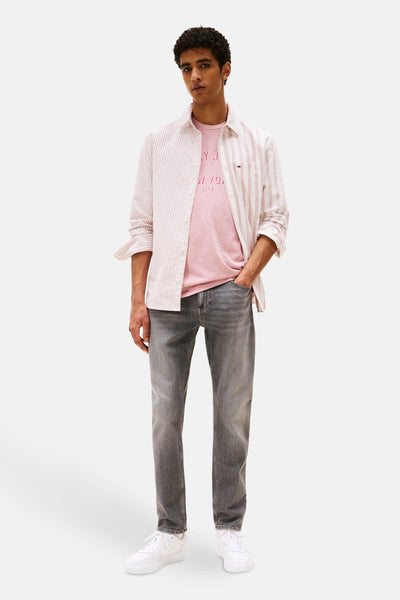Jean fuselé gris moyen en denim de TOMMY JEANS, porté avec une chemise rayée et des baskets blanches.