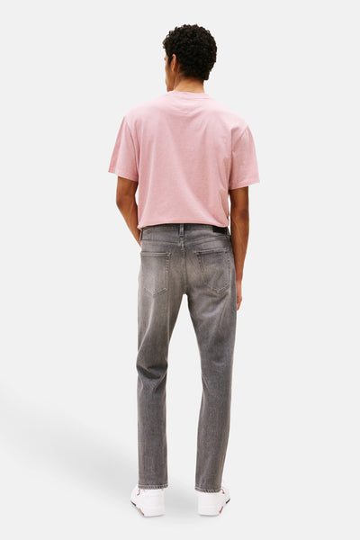 Jean tapered gris moyen en denim de Tommy Jeans, porté avec un t-shirt rose uni.