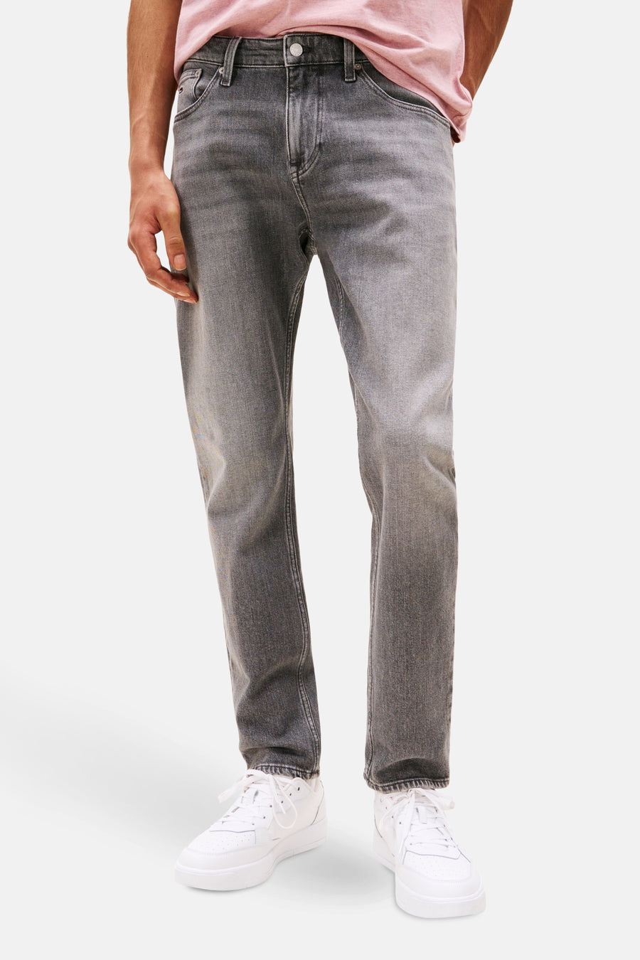 Grijze tapered jeans van TOMMY JEANS, rechte pasvorm, gedragen met witte sneakers.
