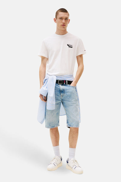 Wit T-shirt met korte mouwen van TOMMY JEANS, met een logo op de borst, gedragen met een spijkerbroekshort en een gestreept overhemd dat aan de taille is geknoopt.