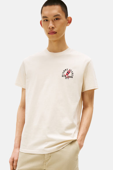 Ecru T-shirt met korte mouwen van TOMMY JEANS, effen, gedragen met een beige cargobroek en witte sneakers.