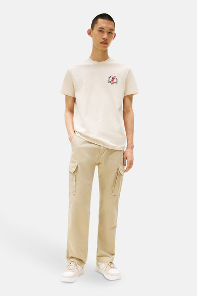 Ecru T-shirt met korte mouwen van TOMMY JEANS, met een opdruk op de voorkant, gedragen met een beige cargobroek.