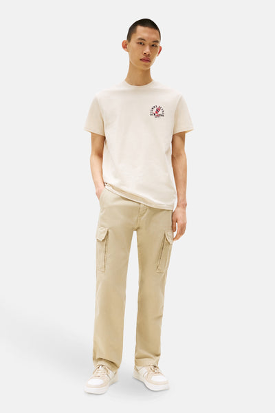Ecru T-shirt met korte mouwen van TOMMY JEANS, met een opdruk op de voorkant, gedragen met een beige cargobroek.