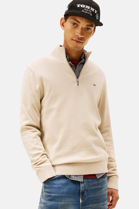 Beige trui met opstaande kraag van Tommy Jeans, gedragen met een wijde broek en een zwarte pet.
