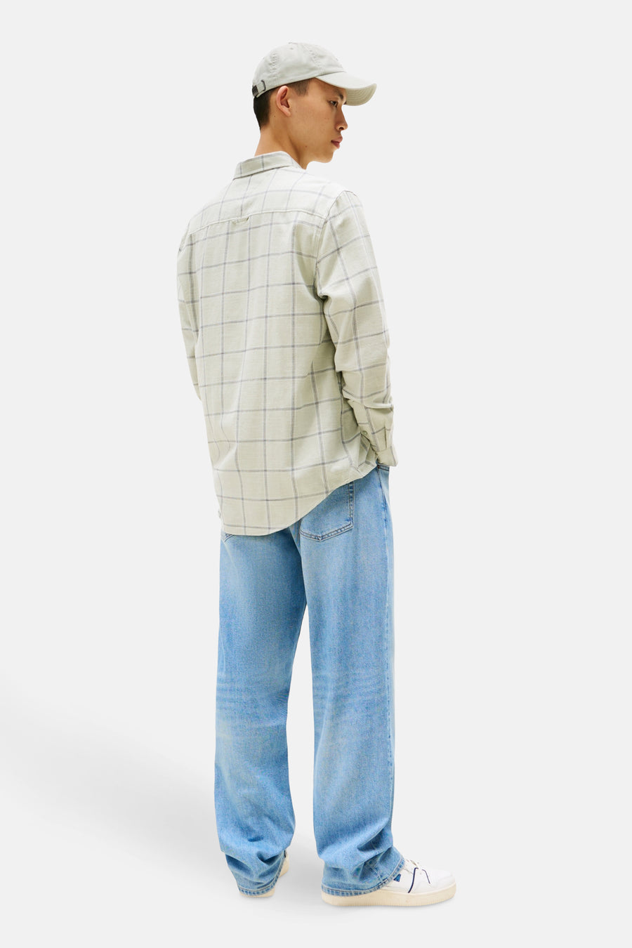 Chemise à manches longues verte à carreaux, de TOMMY JEANS, portée avec un jean ample et une casquette.