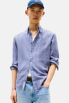 Chemise à manches longues bleue à carreaux par TOMMY JEANS, portée ouverte sur un t-shirt blanc et un jean.